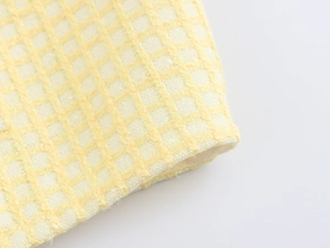 Macro shot of yellow tweed textured waffle fabric detailing the soft fiber weave
