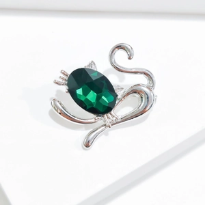 Vue détaillée de la broche chat argentée avec un grand cristal synthétique vert