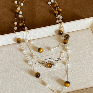 Elegant tiered necklace with tiger eye beads and pearls displayed on jewelry tray
