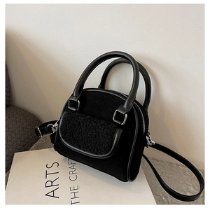 Detail of plush and PU leather black handbag with silver hardware on a magazine