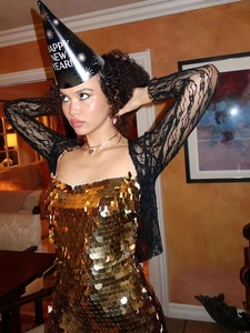 Detail of gold sequin party dress paired with black lace sheer long sleeve overlay