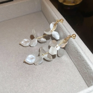 Detailed close-up of floral tassel earrings with matte white petals and baroque pearls