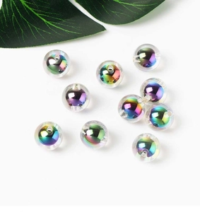 Close-up of clear acrylic beads with AB iridescent finish and a green leaf on white background