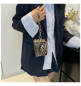Detail shot of a mini animal print handbag with matching strap held by a model