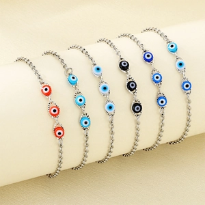 Minimalist stainless steel evil eye bracelets in multiple colors on a cylindrical display