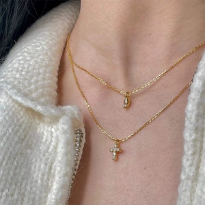 Detail of layered gold S925 silver necklace with cross and marquise drop pendant
