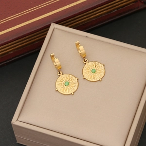 Macro shot of gold-plated hoop earrings with green gemstone and sunburst design
