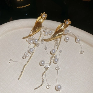 Detail of elegant gold leaf earrings with hanging pearls, tassels, and sparkling zircons