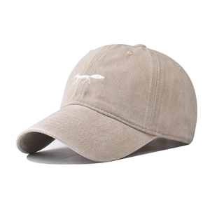 Close-up of white fox embroidery on washed cotton baseball cap with vintage texture