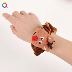 Brown plush reindeer scrunchie with red nose on wrist against white background