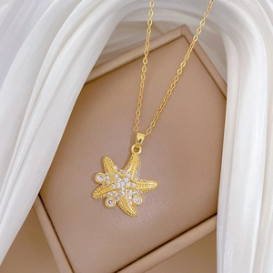 Macro detail of a gold starfish pendant necklace with pavé zircons on a beige cushion