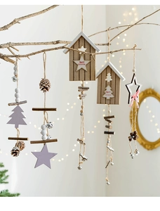 Close-up of wooden Christmas ornaments with stars, bells, and pine cones on branches