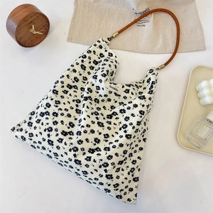 Detail of vintage floral canvas tote bag with brown leather handles and brand tag