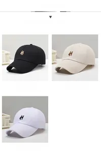 Close-up of embroidered H letters on black, khaki and white cotton baseball caps