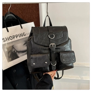 Détail du sac à dos vintage en cuir noir avec boucles argentées et design multi-poches