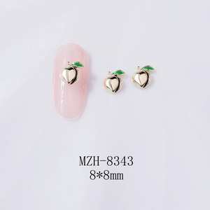 Macro detail of 8x8mm gold peach nail charms with green leaves on a white background