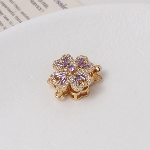 Macro detail of gold floral pearl clasp with purple and white cubic zirconia stones