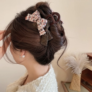 Detail of tweed bow hair claw clip in brown and beige colors worn on long hair