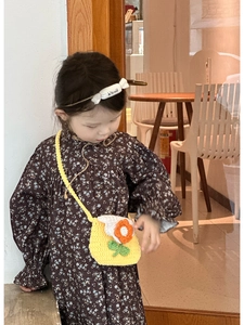 Detail of yellow knit crossbody bag with sunflower design worn by a child in floral dress
