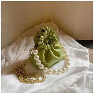 Detail of green ruched mini bag with large pearl handle and golden chain strap