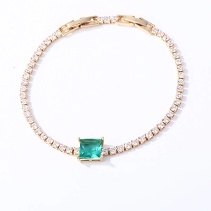 Detail of 18K gold tennis bracelet with emerald cut green stone and white zircon stones
