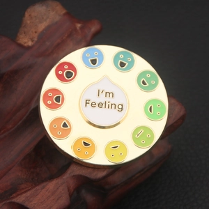Round enamel pin with colorful emotion faces and I'm Feeling text on wood base