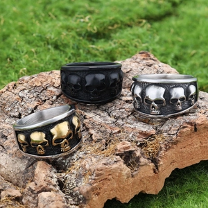 Detailed close-up of punk style skull rings in black, silver and gold on tree bark background