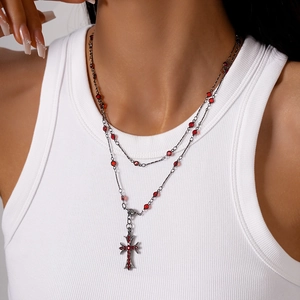 Close-up of gothic double-layer necklace with red bead accents and a cross pendant