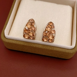 Gros plan de boucles d'oreilles en U avec cristaux champagne sur velours crème