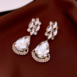 Close-up of teardrop crystal drop earrings on brown satin, showing sparkling zircon detail