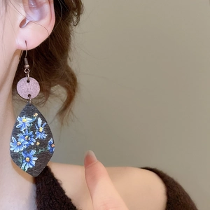 Detail of wooden leaf-shaped earring with blue floral prints and vintage design