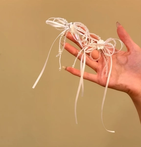 Primo piano di una raffinata collana a fiocco con nastro e perle bianche stile francese.