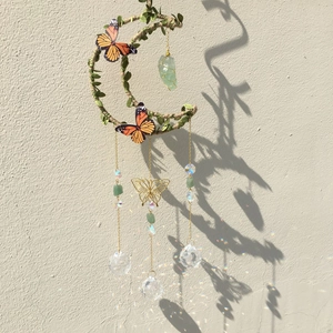 Moon-shaped suncatcher with green leaves, butterflies, and sparkling crystal balls
