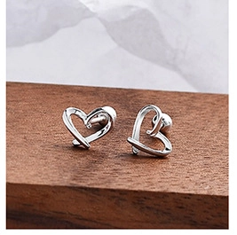 Macro shot of polished heart-shaped S925 sterling silver stud earrings on a wood surface