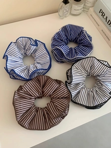 Set of oversized blue and black striped fabric hair scrunchies on a cream background