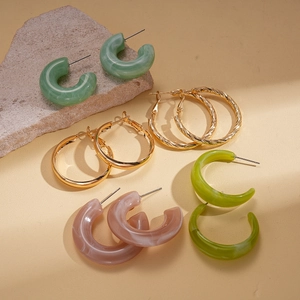 Detail of 10-piece acrylic resin and gold hoop earring set on natural stone base