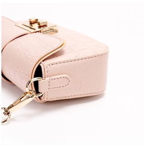 Close-up of pink crocodile texture bag with golden metal hardware and strap buckle
