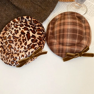 Detail of vintage leopard and plaid berets with velvet bows on a warm aesthetic background