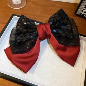 Detail of elegant double-layered lace bow hair clip with black sequins and dark red satin