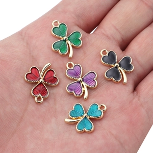 Colorful clover alloy pendants for DIY jewelry making shown on hand for scale
