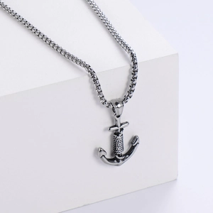 Vintage stainless steel anchor pendant necklace with box chain on white geometric pedestal