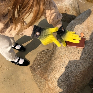 Outdoor close-up of rainbow gradient knit gloves showing warm wool texture and touch screen tips
