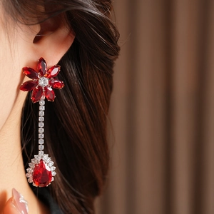 Detailed close-up of model wearing floral red zircon drop earrings with shimmering tassels