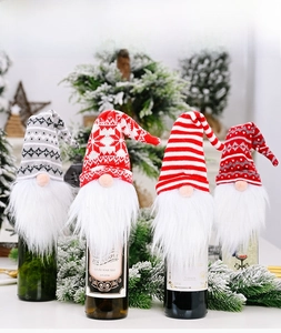 Set of four knitted Christmas gnome wine bottle covers with white beards and festive patterns