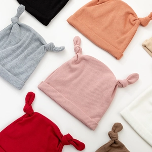 Vue à plat de bonnets bébé en tricot côtelé coloré avec de jolis bois à double nœud