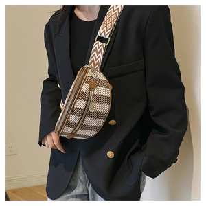 Chic brown checkered chest bag with wide geometric strap worn over a black blazer
