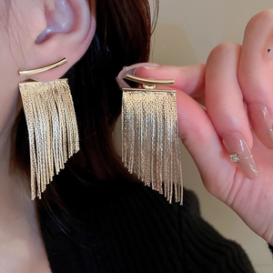 Detail shot of golden metal tassel earrings shown on a model for elegant styling