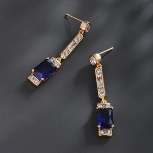 Detailed close-up of rectangular blue crystals and micro-pave zircons on gold drop earrings