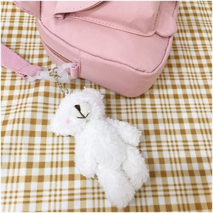 Detailed view of pink canvas shoulder bag with a cute white plush bear keychain