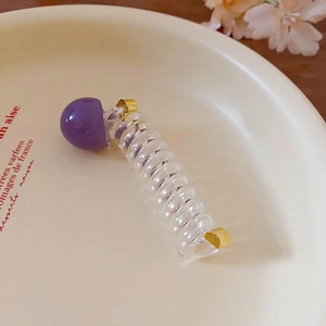 Close-up detail of clear telephone wire hair tie with purple bead and metallic accents.